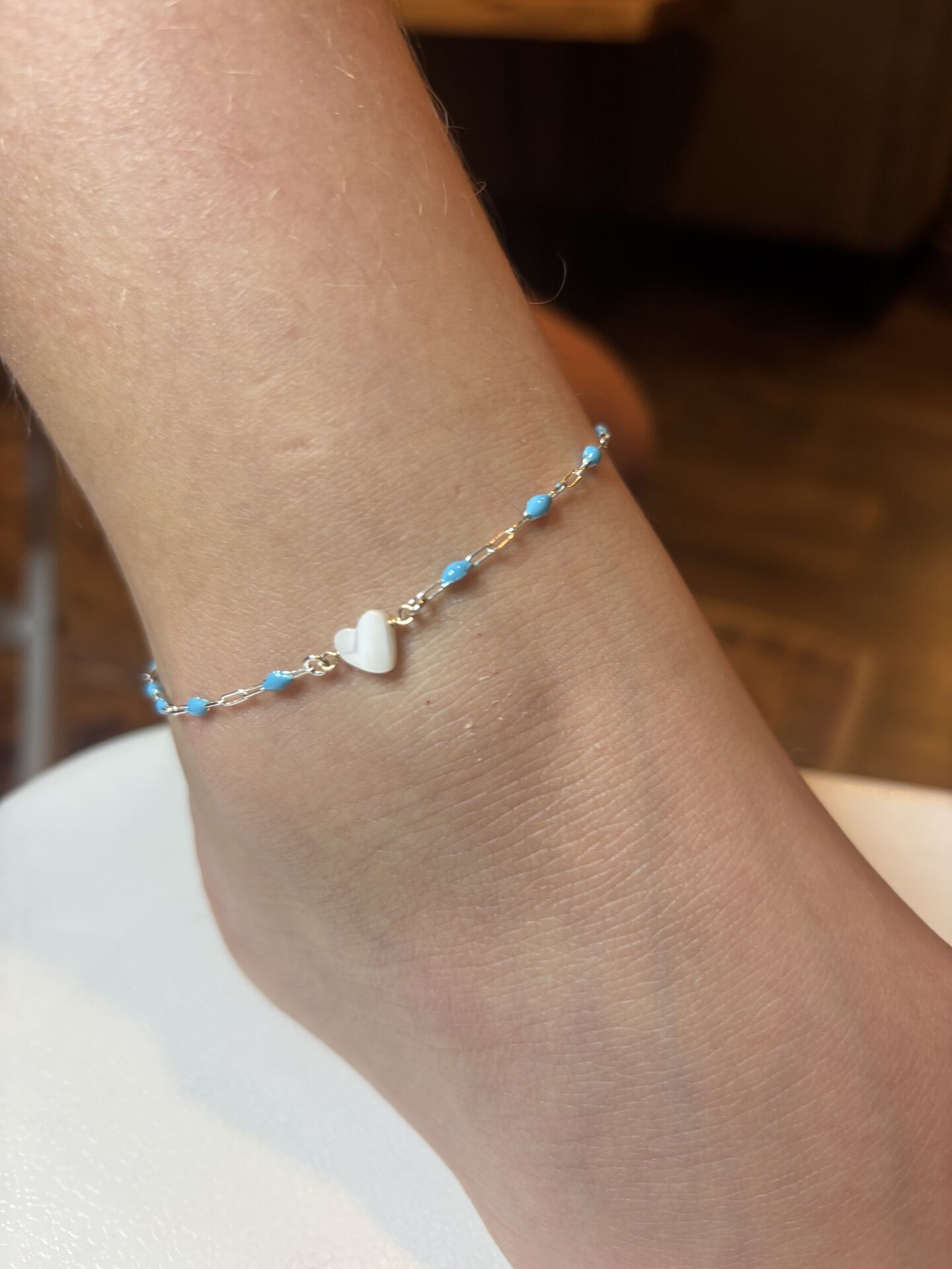 Gold bracelet with blue beads and a white heart charm