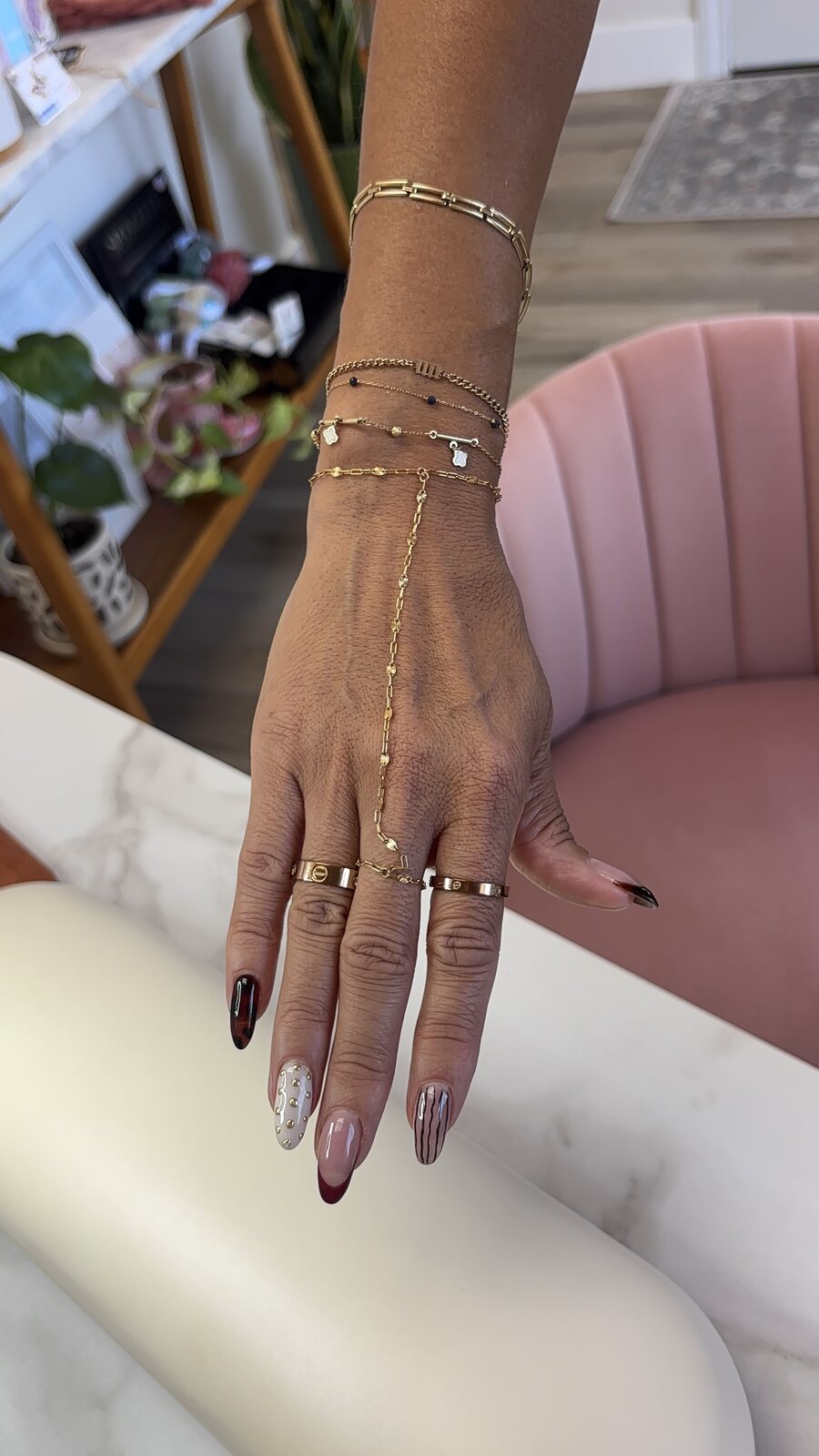 Layered gold bracelets and a hand chain on a client