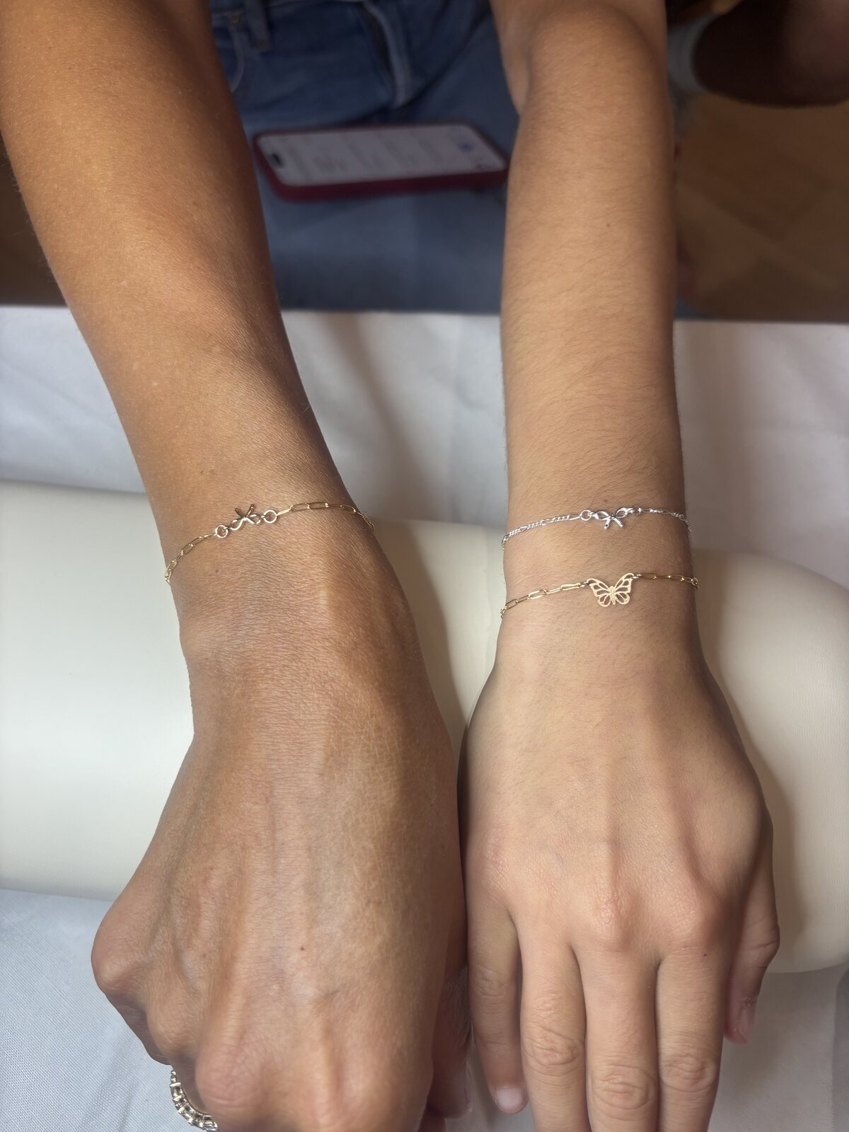 Two clients wearing butterfly charm bracelets